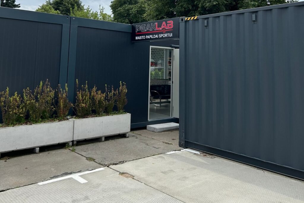 PeakLab parduotuvės durys su raudona iškaba tolimiausiame kiemo kampe